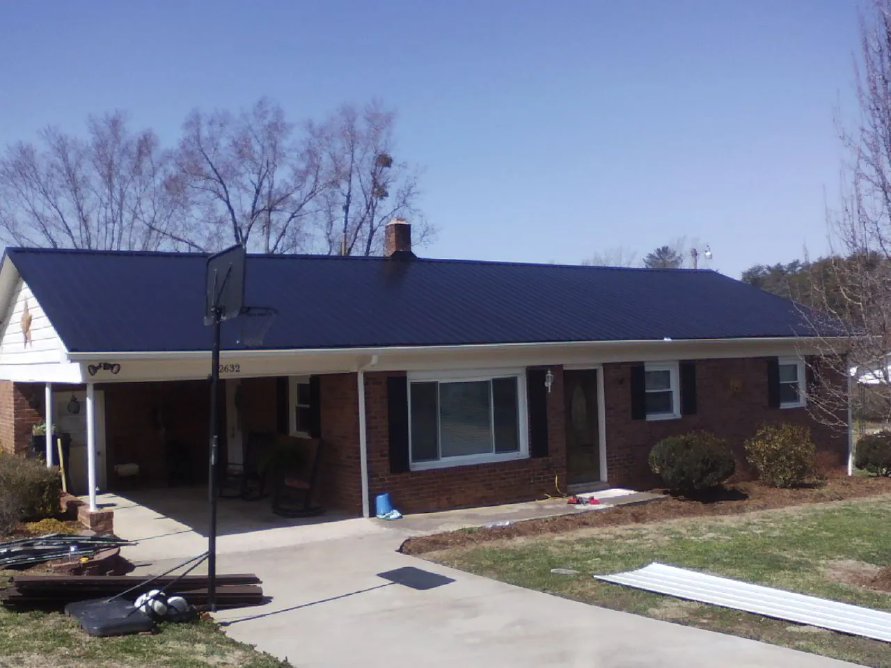 Finished dark blue metal roof on a brick ranch with a carport in Becket