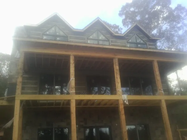 Dormers and porch framing on a large log home under construction — Roof Coating work by our crew in Becket