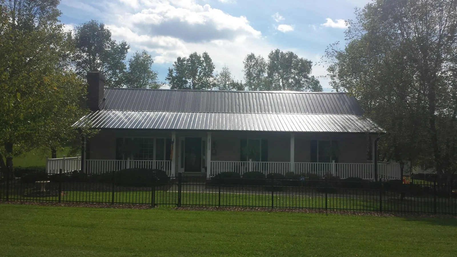 Gray metal roof on a brick ranch with a full width front porch — Gutter Guard Installation work by our crew in Becket