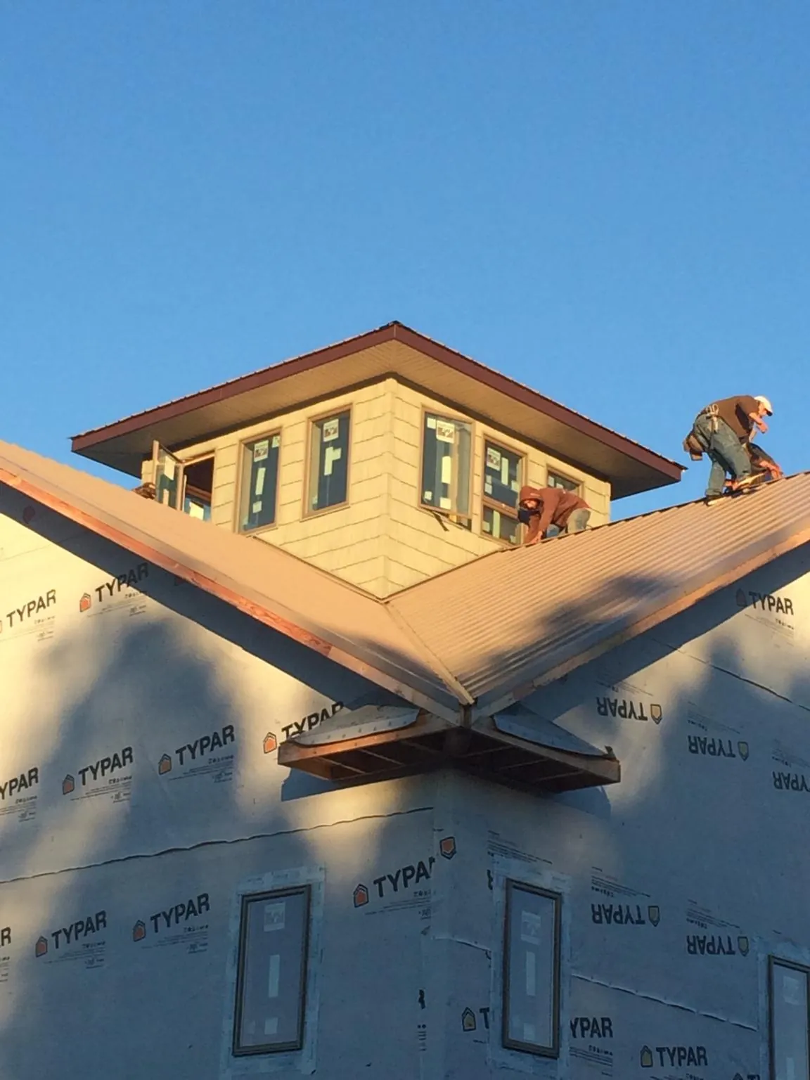 Roofers working around a rooftop cupola on a new metal roof at sunset — Roof Waterproofing in Becket by Roofing Brothers